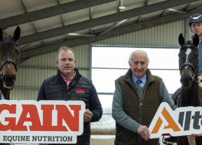 men standing in stable with horses and GAIN signs